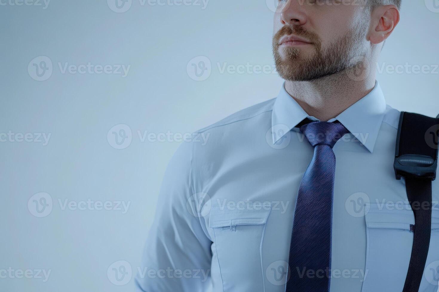 A border control officer is standing in a well-lit area, dressed in a professional uniform. His expression reflects focus and readiness as he performs his duties, ensuring security and safety. photo