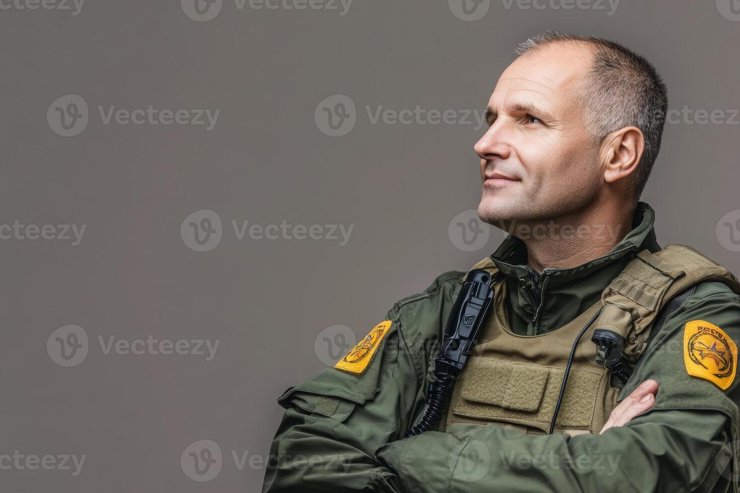 A border control officer is standing with arms crossed, exuding confidence. He wears a uniform featuring a badge, ready to uphold security protocols during his shift at the border. photo