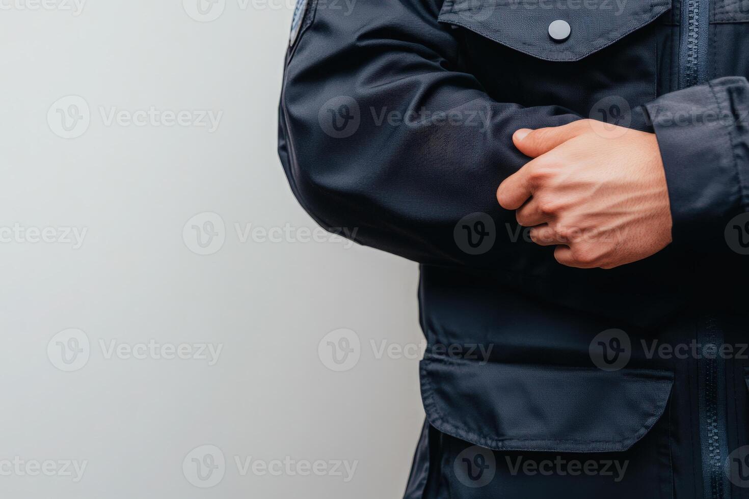 A border control officer stands with arms crossed, dressed in a dark uniform. The clean and solid background emphasizes the officers professionalism and readiness for duty. photo