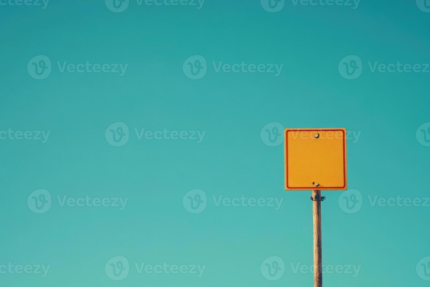 A solitary yellow border crossing sign is prominently displayed, set against a vast, clear blue sky. The scene radiates tranquility in an open space, devoid of other distractions. photo