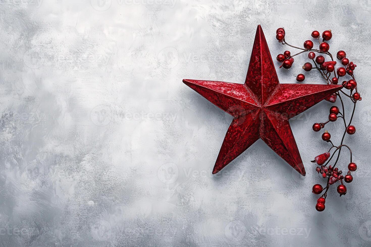 A striking red Christmas star is placed alongside a cluster of red berries, all set against a clean gray background. This festive arrangement captures the spirit of the holiday season. photo