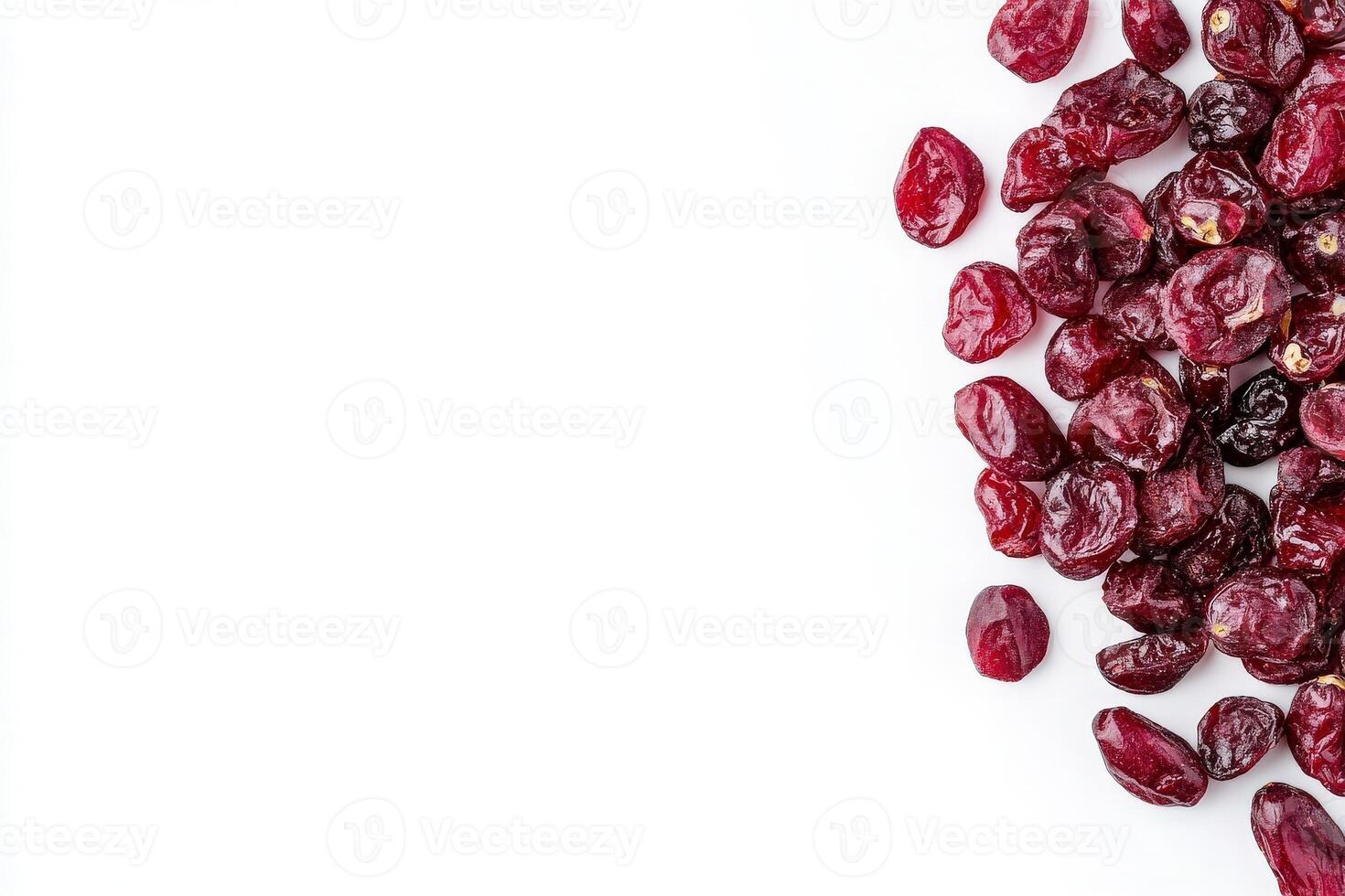 A collection of dried cranberries is displayed on a smooth, solid white surface, highlighting their deep red hue and wrinkled texture. These nutritious fruit snacks are perfect for various dishes. photo
