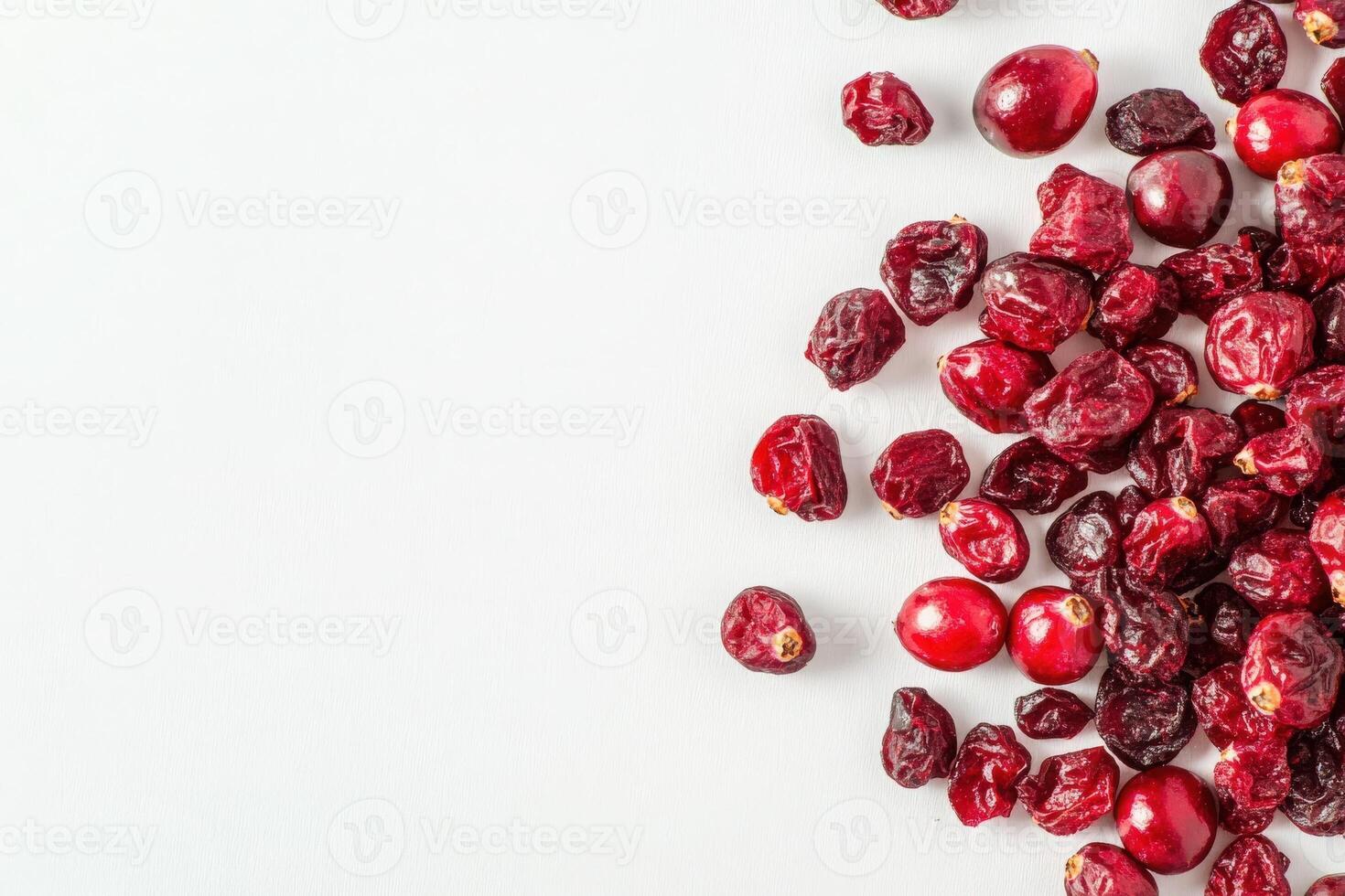 A collection of dried cranberries rests on a spotless white background, showcasing their deep red hue and varied shapes. Their vibrant appearance suggests a healthy snack option. photo