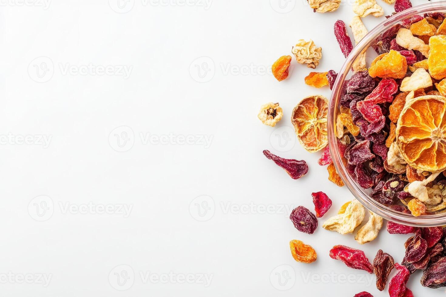 A vibrant mix of dried fruits is arranged around a clear bowl, showcasing an array of textures and colors. This healthy snack choice highlights the natural appeal of fruits. photo