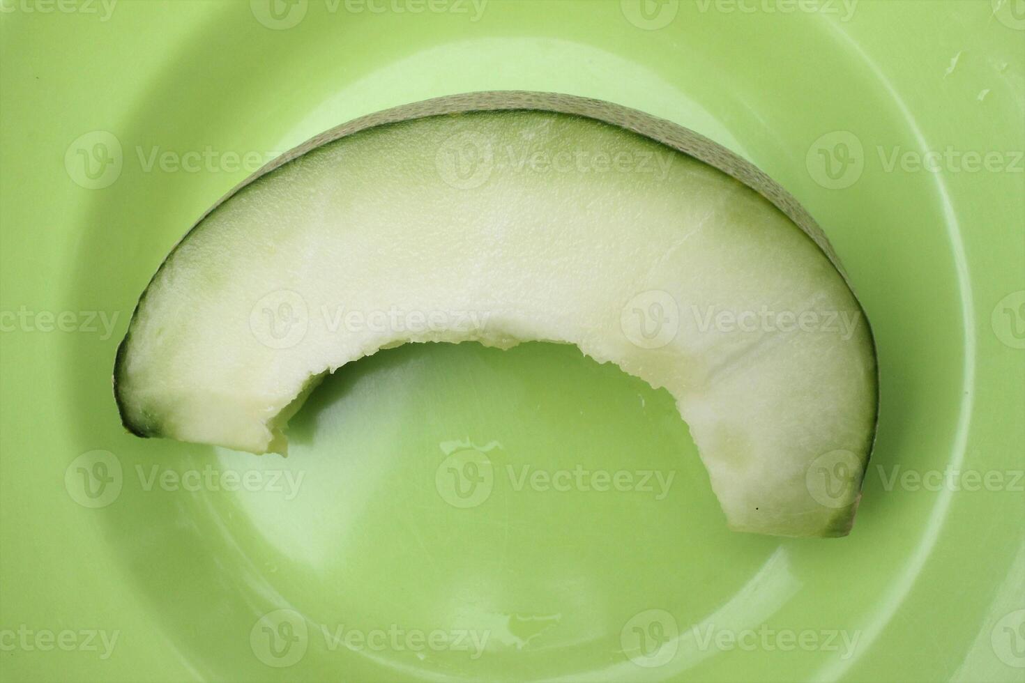 A slice of melon on a green plate photo