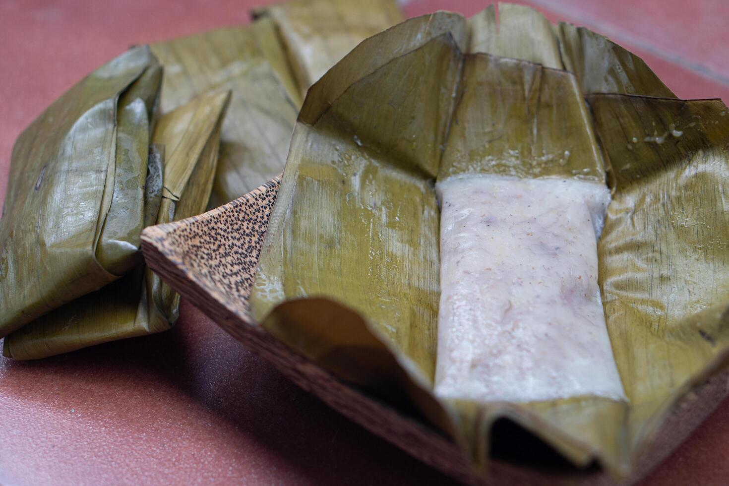 Traditional Thai banana cake. Wrapped in banana leaves. Steamed until cooked and delicious.Placed on a plate made from coconut palm. photo