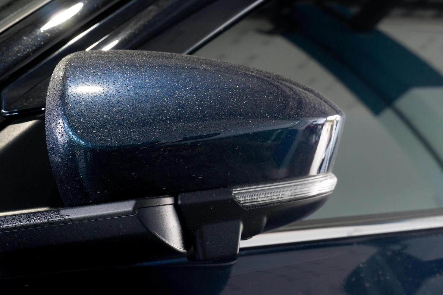 Mirror is painted a dark blue color and has drop of water rain around the edge. The mirror casing is curved and has a small. rectangular shape. The mirror itself is not visible in the image. photo