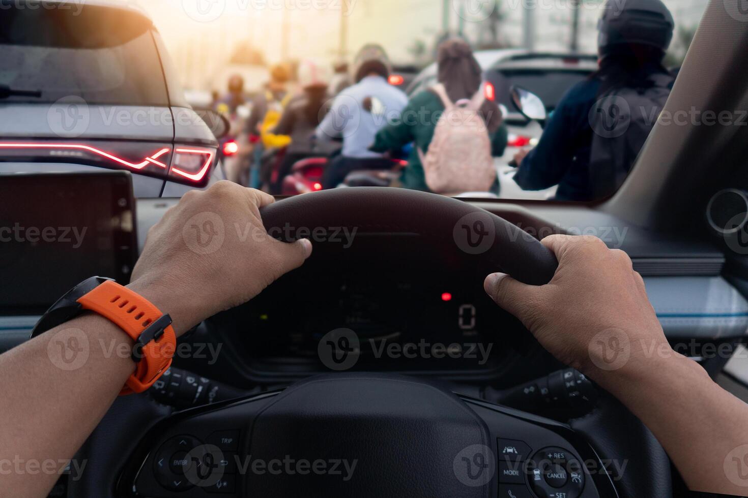 Hand of driver gripping on steering wheel of car. View from the driver perspective shows a traffic jam ahead. with people walking on the sidewalk. Traffic jam on business time. photo