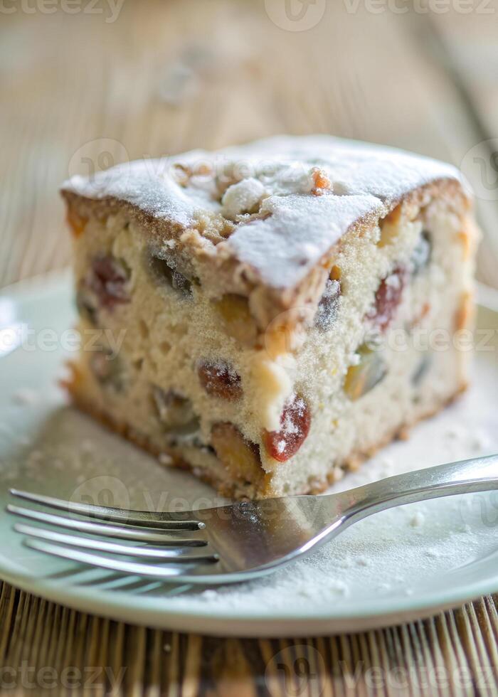 Close-up of a slice of fruitcake with powdered sugar, a fork halfway through photo