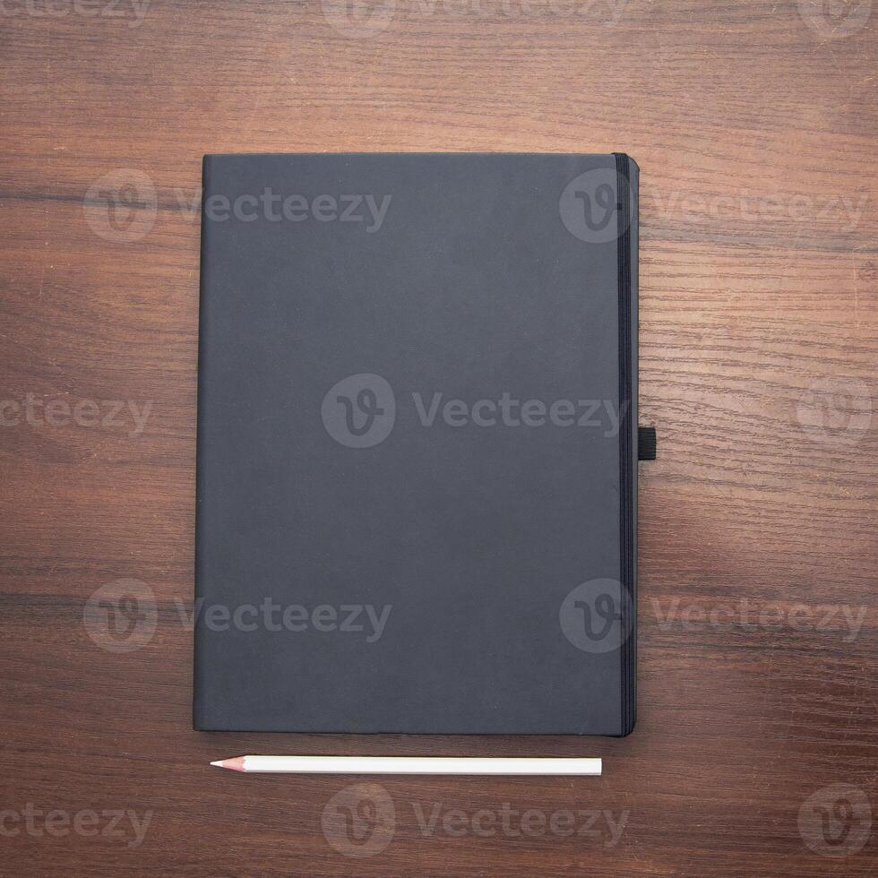Black notebook with pencil on wooden table photo