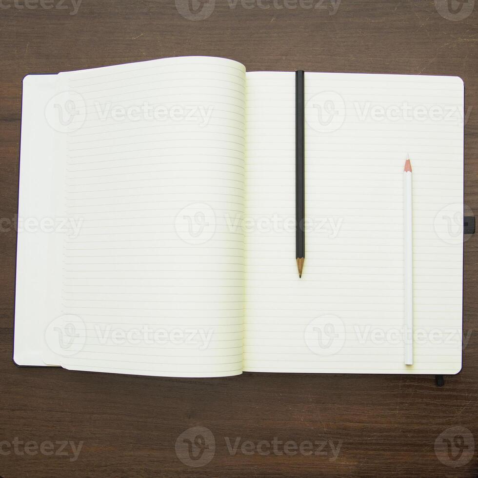 Open notebook and pencil on wooden table top view photo