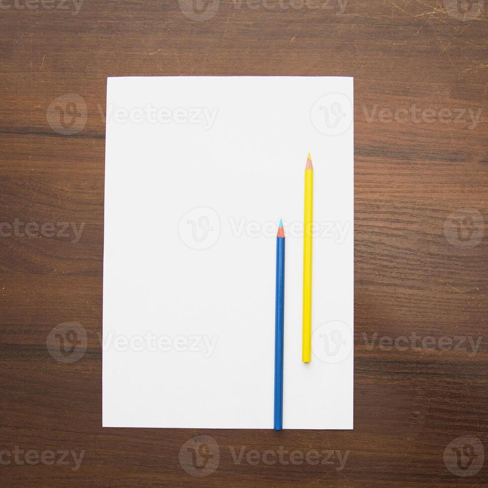 A white sheet with two yellow pencils on top photo