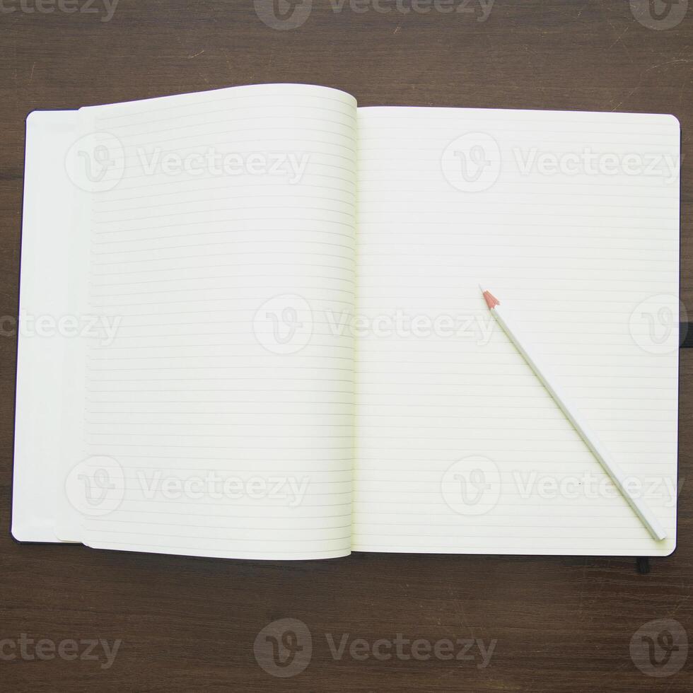 An open notebook with a pencil on a wooden table photo