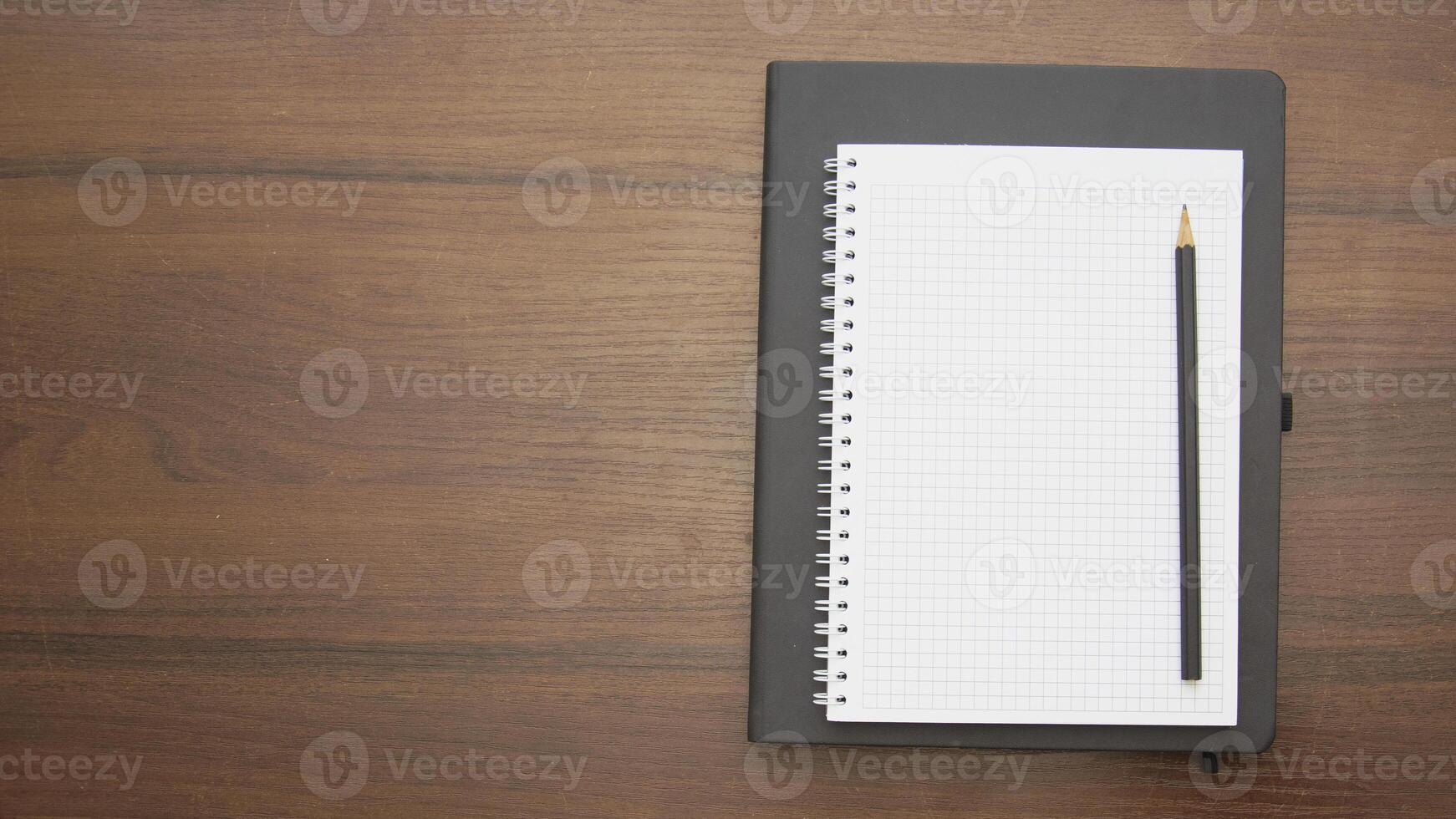 Notebook with pencil on wooden table top view photo