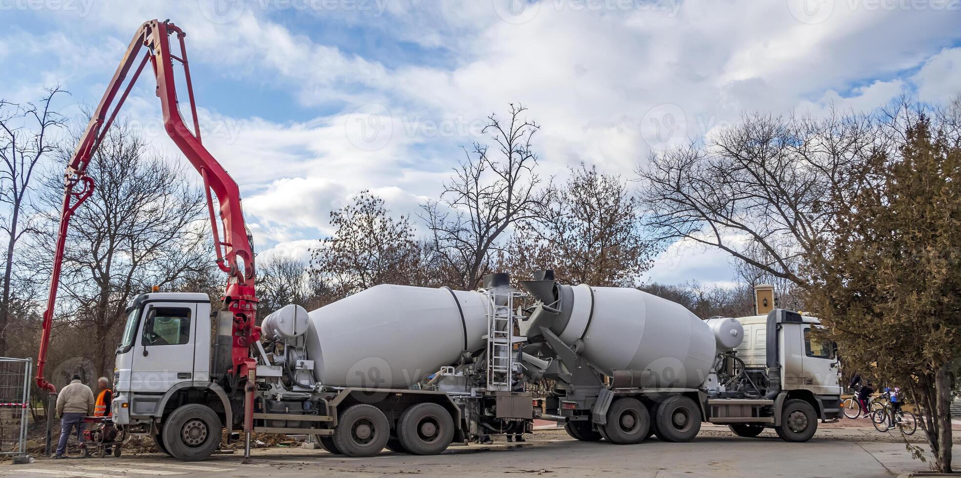 Heavy mixer concrete trucks loading concrete at a construction site with a mixer photo