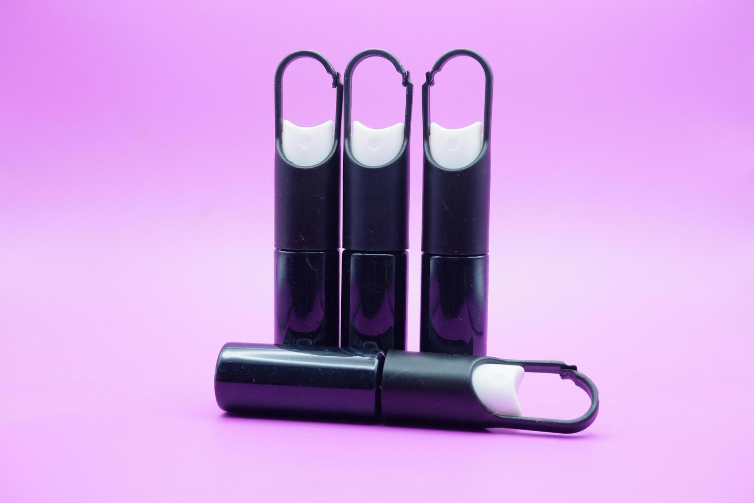 mini sprayer bottles isolated on purple background. four sprayer bottles with hangers photo