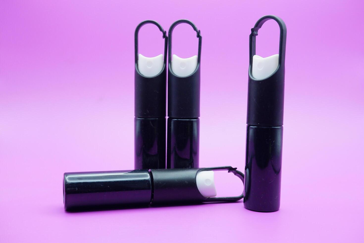 mini sprayer bottles isolated on purple background. four sprayer bottles with hangers photo