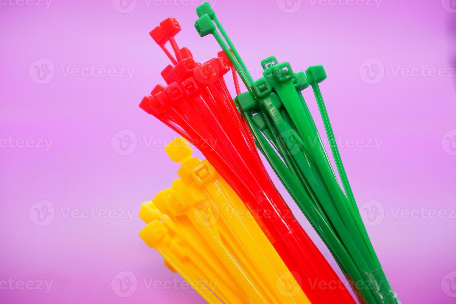 bundle of zip ties isolated on purple background. zip ties in red, green, and yellow. Cable ties or cable ties, straps that can be used for various purposes. photo