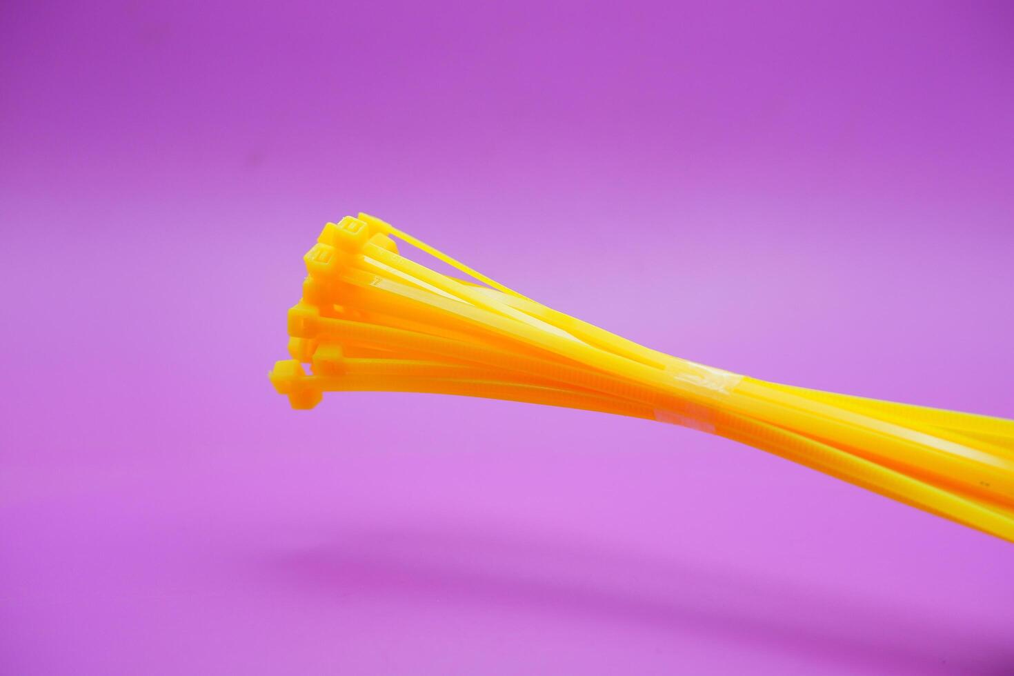 bundle of yellow zip ties isolated on purple background. Cable ties or cable ties, straps that can be used for various purposes. photo