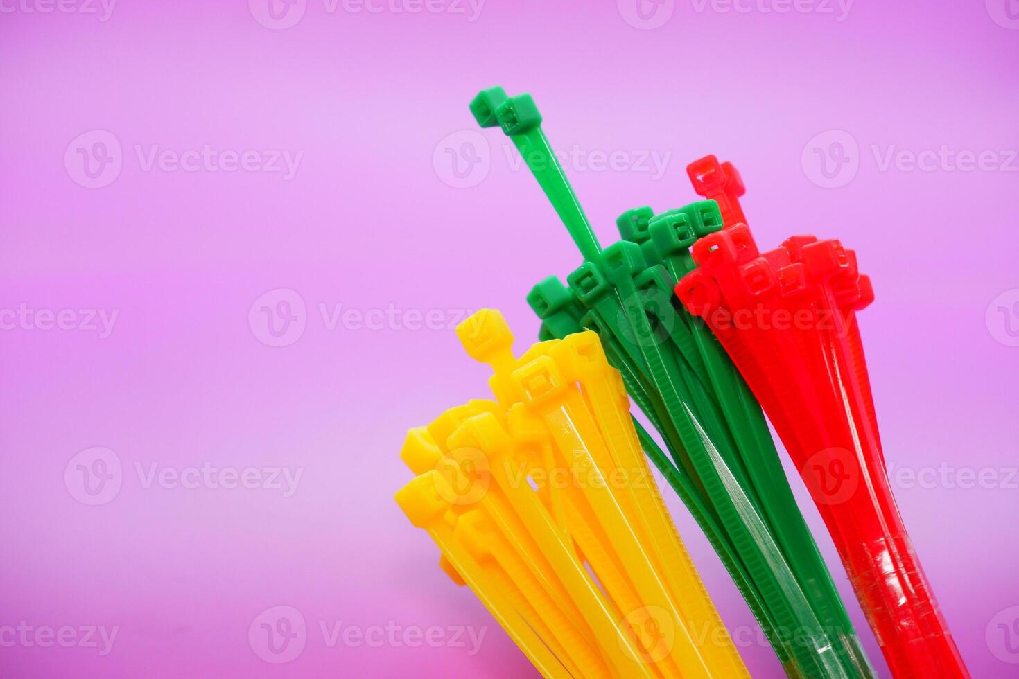 bundle of zip ties isolated on purple background. zip ties in red, green, and yellow. Cable ties or cable ties, straps that can be used for various purposes. photo