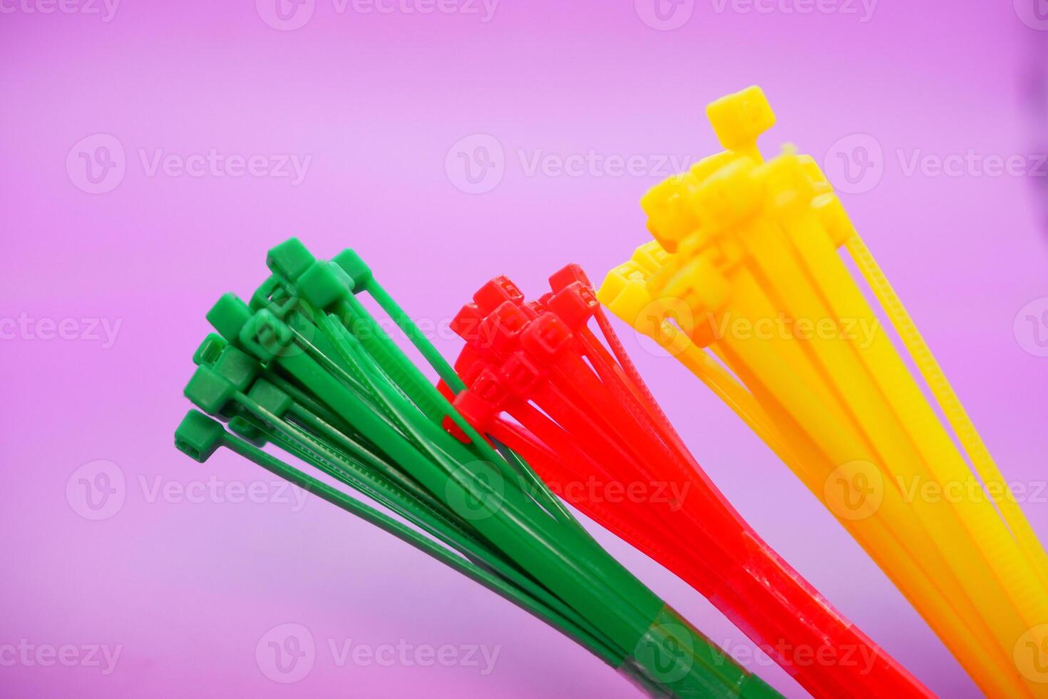 bundle of zip ties isolated on purple background. zip ties in red, green, and yellow. Cable ties or cable ties, straps that can be used for various purposes. photo