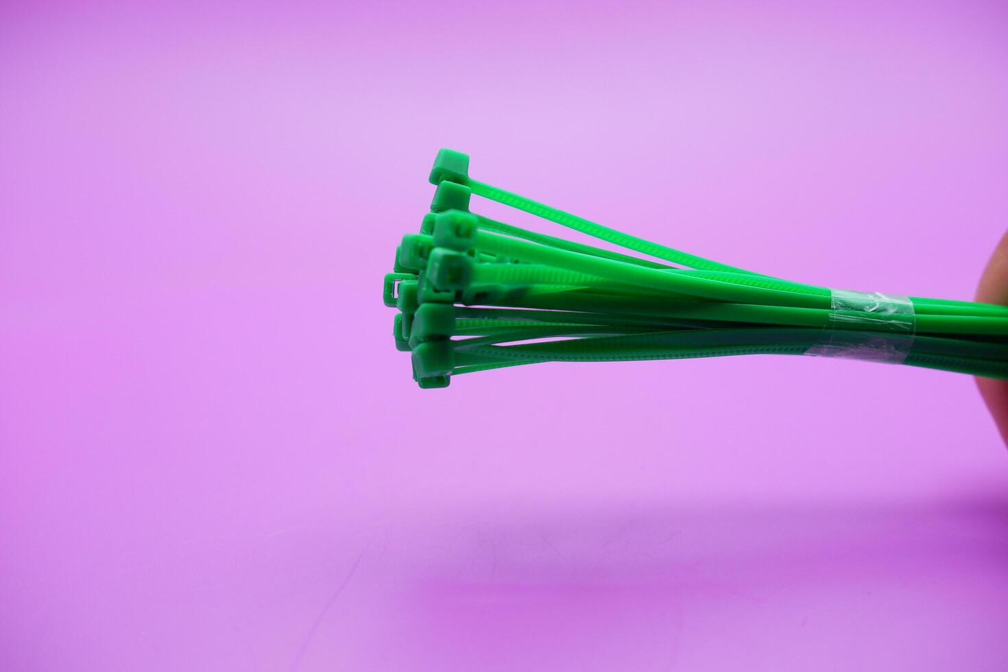 bundle of green zip ties isolated on purple background. Cable ties or cable ties, straps that can be used for various purposes. photo