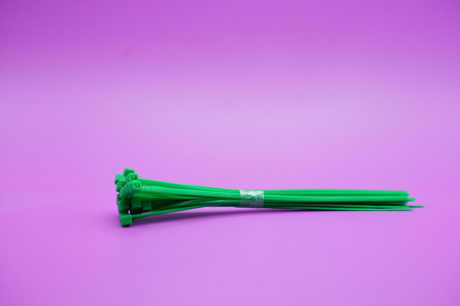 bundle of green zip ties isolated on purple background. Cable ties or cable ties, straps that can be used for various purposes. photo