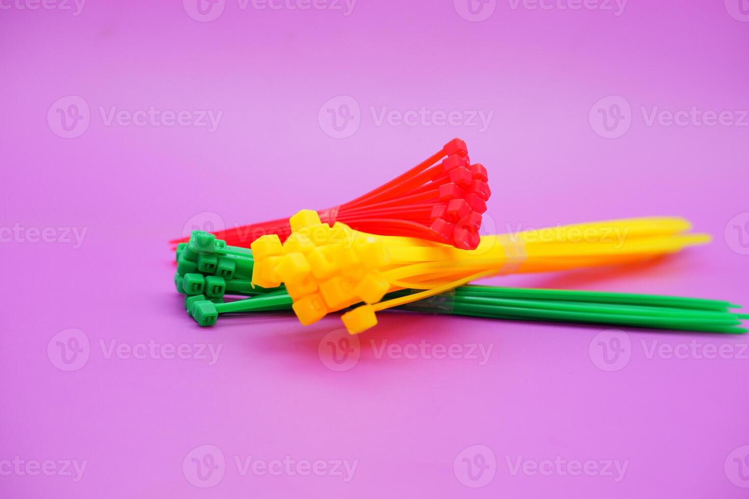 bundle of zip ties isolated on purple background. zip ties in red, green, and yellow colors arranged in a stacked manner. Cable ties or cable ties, straps that can be used for various purposes. photo