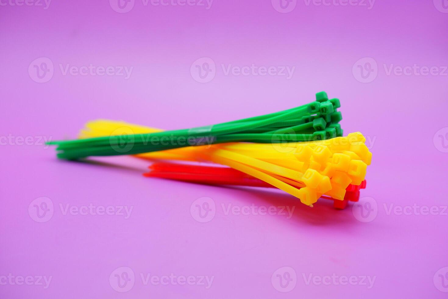 bundle of zip ties isolated on purple background. zip ties in red, green, and yellow colors arranged in a stacked manner. Cable ties or cable ties, straps that can be used for various purposes. photo