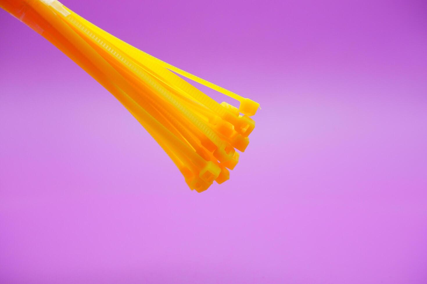 bundle of yellow zip ties isolated on purple background. Cable ties or cable ties, straps that can be used for various purposes. photo