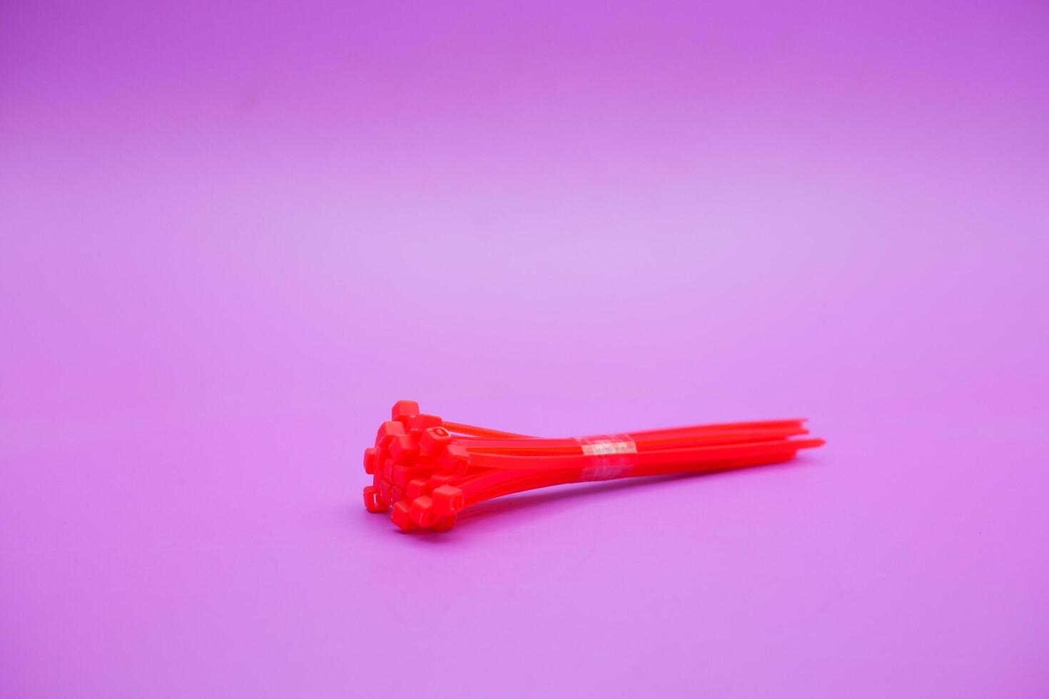bundle of red zip ties isolated on purple background. Cable ties or cable ties, straps that can be used for various purposes. photo