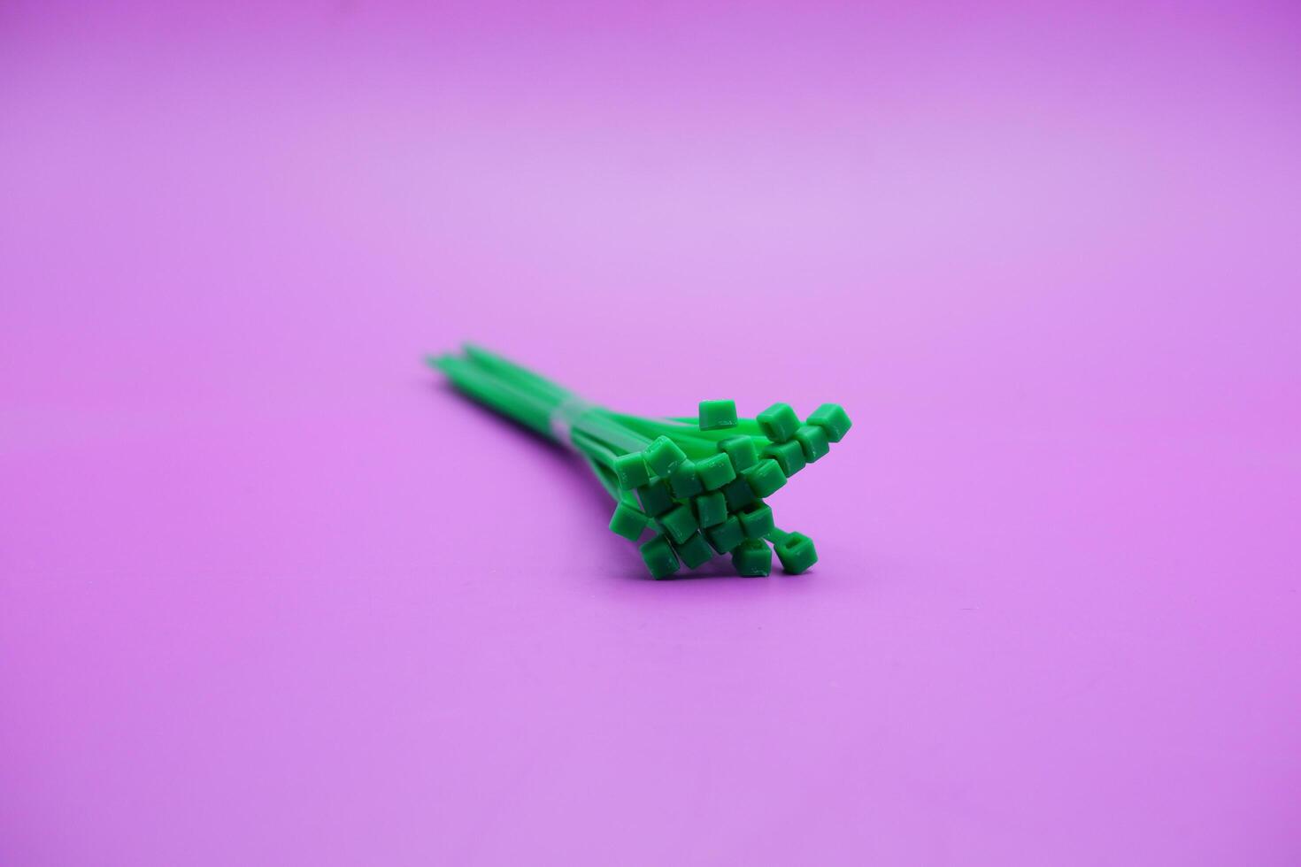 bundle of green zip ties isolated on purple background. Cable ties or cable ties, straps that can be used for various purposes. photo