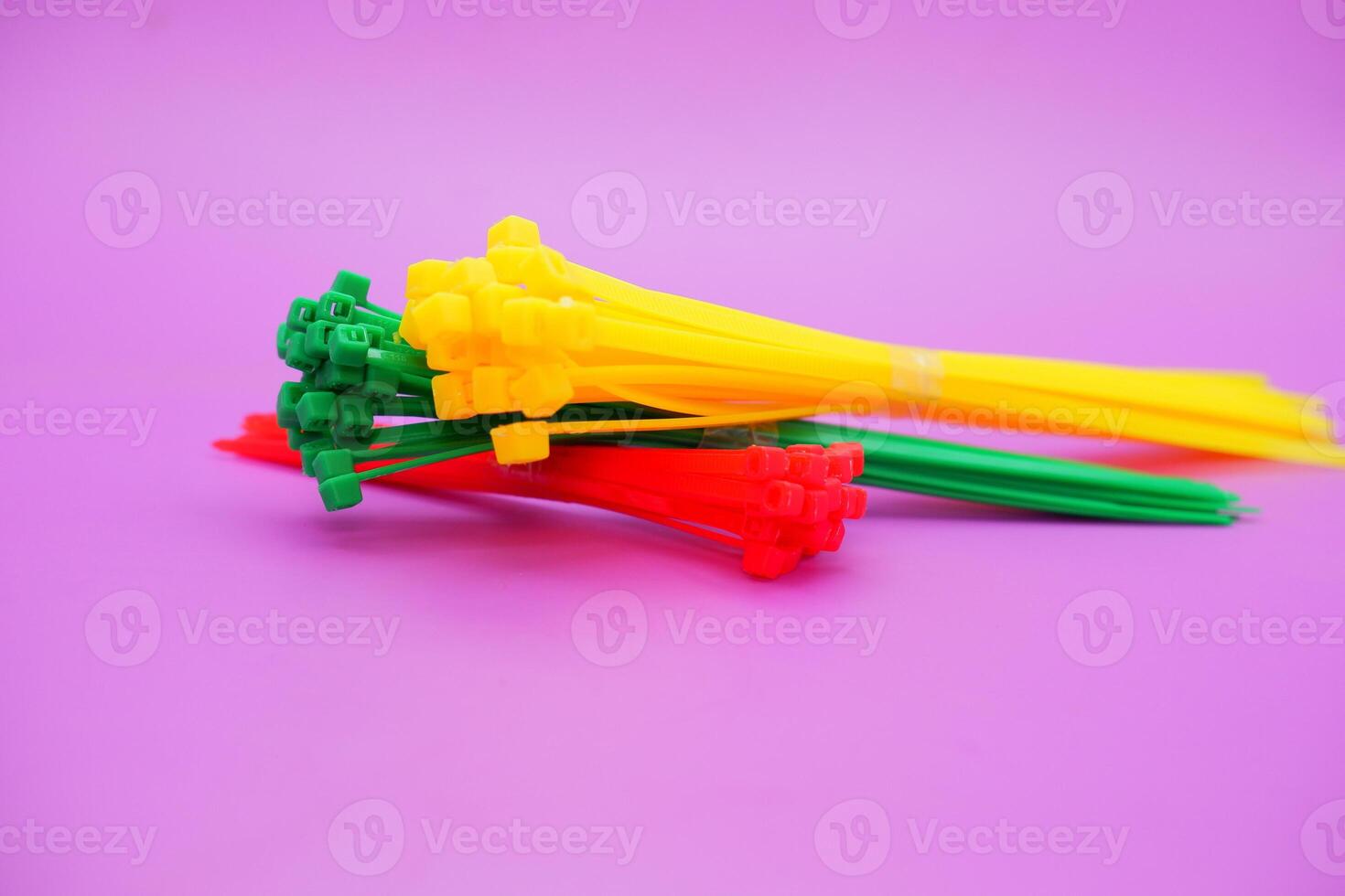 bundle of zip ties isolated on purple background. zip ties in red, green, and yellow colors arranged in a stacked manner. Cable ties or cable ties, straps that can be used for various purposes. photo