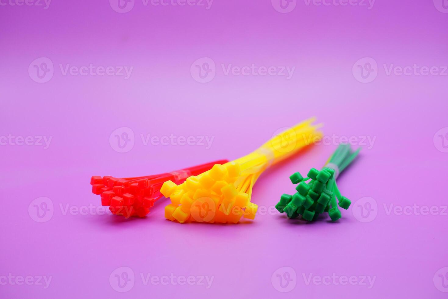 bundle of zip ties isolated on purple background. zip ties in red, green, and yellow colors arranged in a row. Cable ties or cable ties, straps that can be used for various purposes. photo