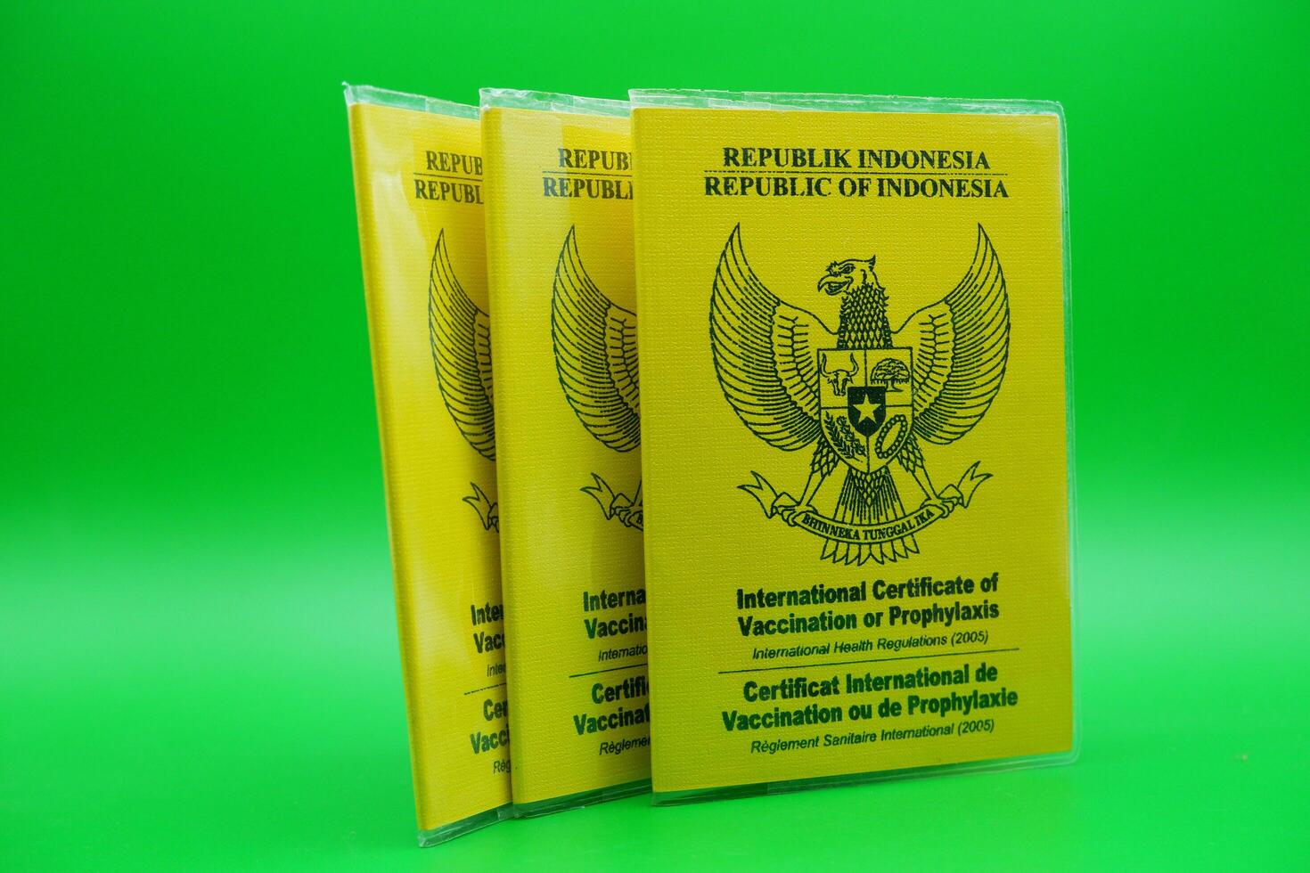 international certificate of vaccination or prophylaxis isolated on green background. 3 yellow books as a sign of vaccination. yellow book of vaccines from indonesia photo