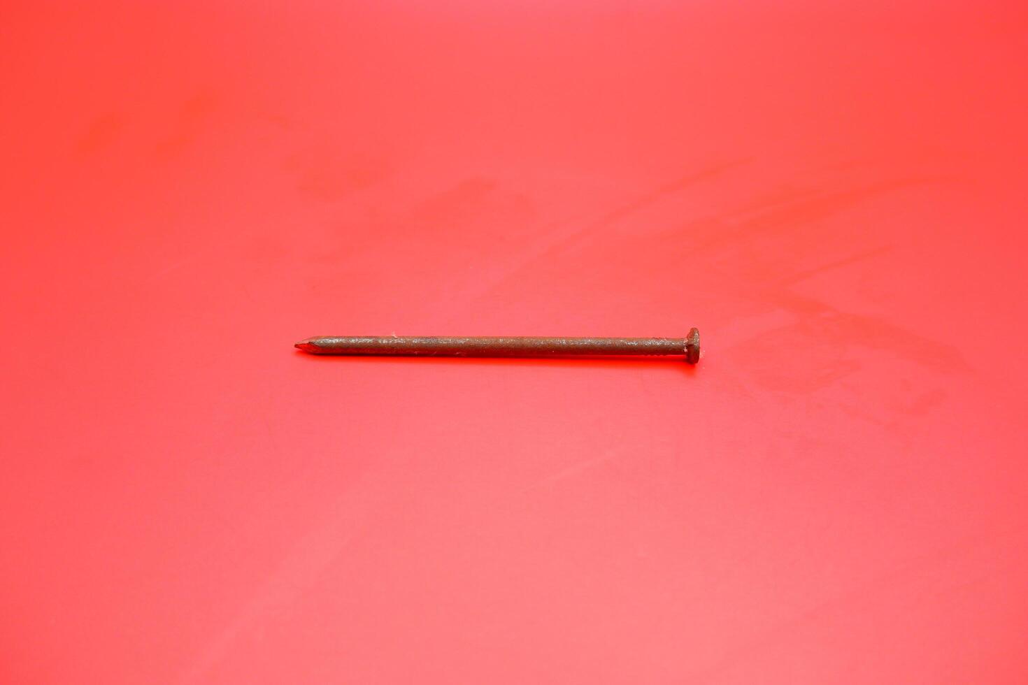 rusty nail isolated on red background. rusty nail with a length of approximately 10 cm photo