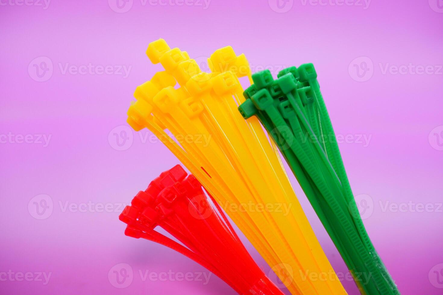 bundle of zip ties isolated on purple background. zip ties in red, green, and yellow. Cable ties or cable ties, straps that can be used for various purposes. photo
