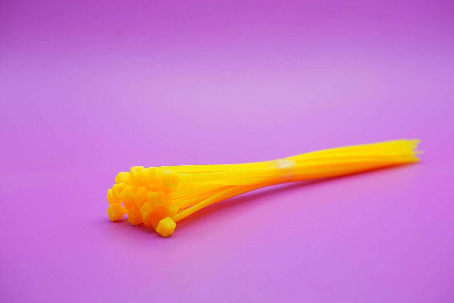 bundle of yellow zip ties isolated on purple background. Cable ties or cable ties, straps that can be used for various purposes. photo