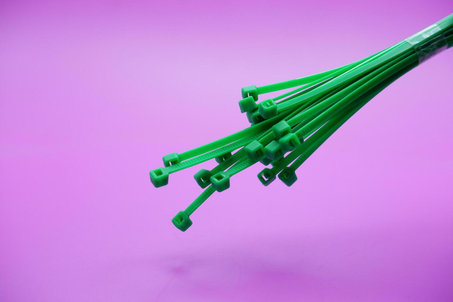 bundle of green zip ties isolated on purple background. Cable ties or cable ties, straps that can be used for various purposes. photo