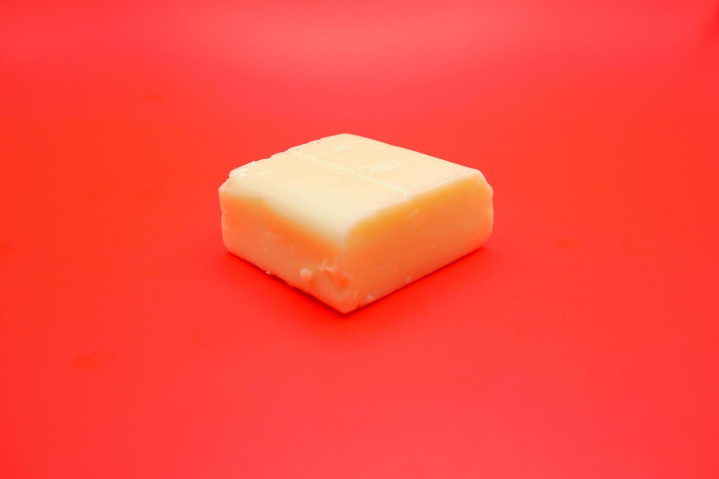 cube shaped cheese isolated on red background. mozzarella cheese that melts easily photo