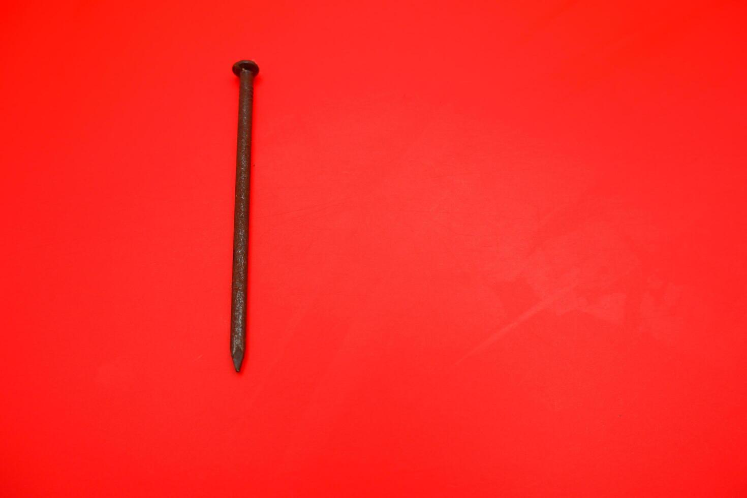 rusty nail isolated on red background. rusty nail with a length of approximately 10 cm photo
