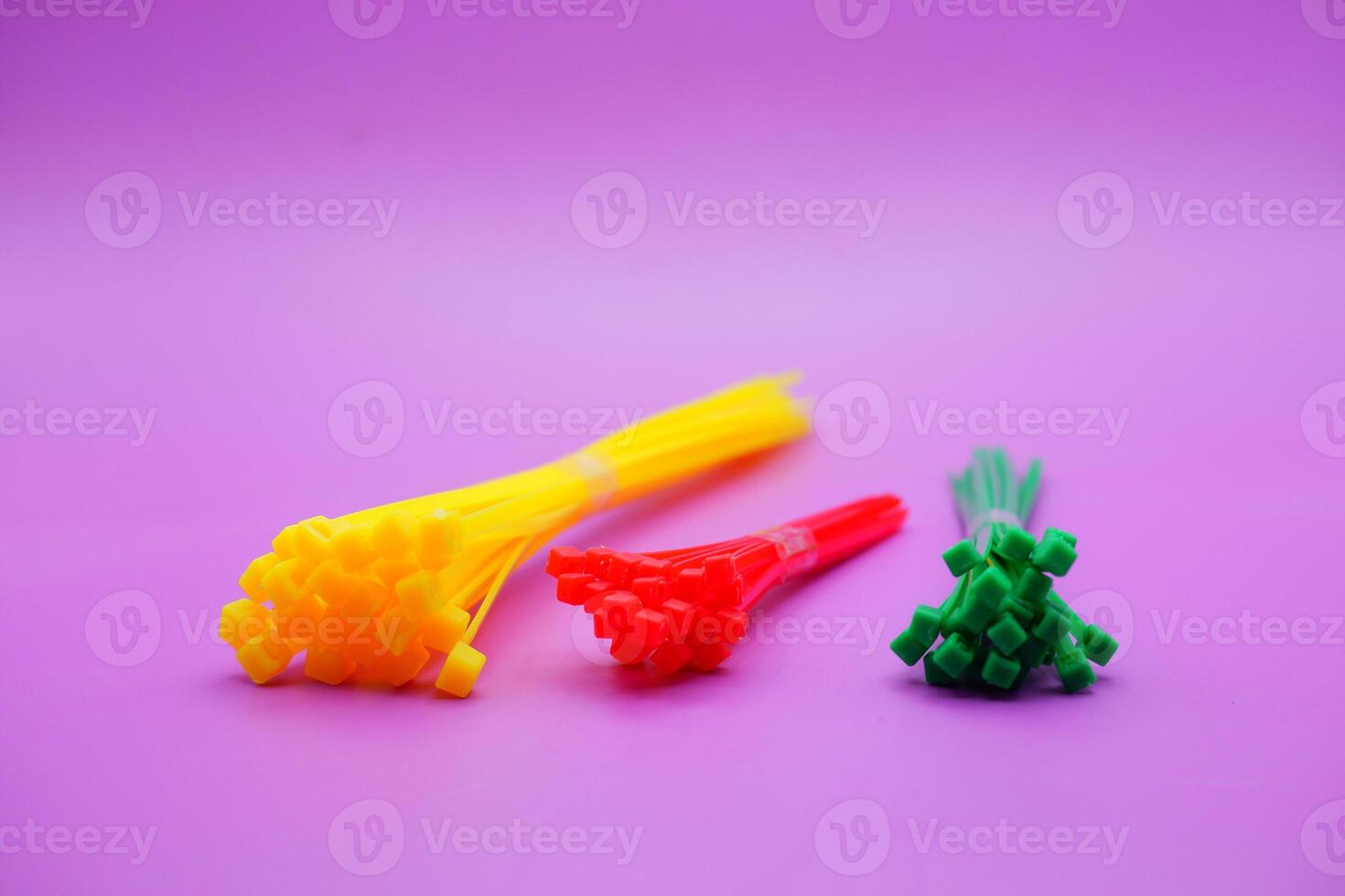 bundle of zip ties isolated on purple background. zip ties in red, green, and yellow colors arranged in a row. Cable ties or cable ties, straps that can be used for various purposes. photo