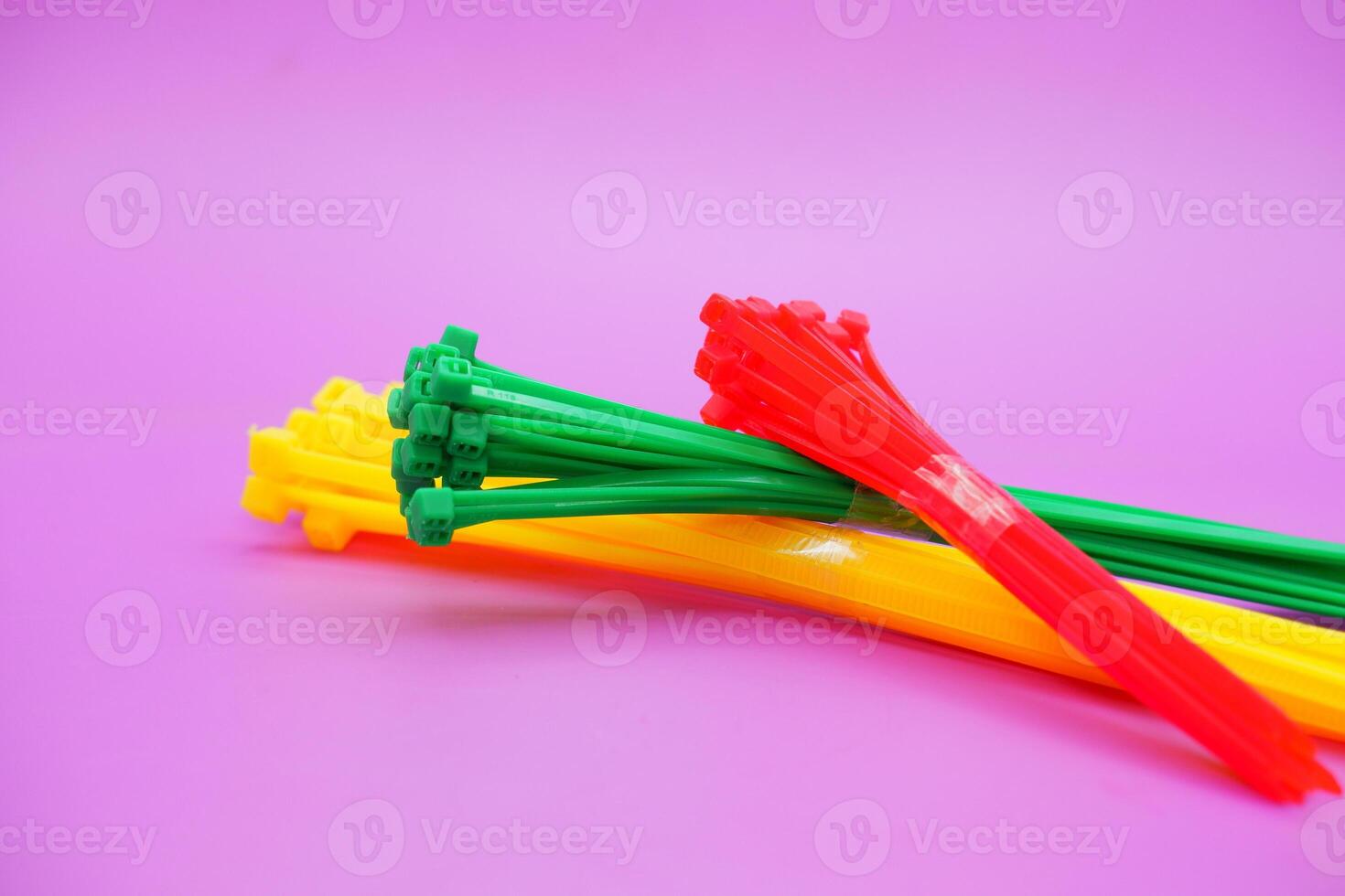 bundle of zip ties isolated on purple background. zip ties in red, green, and yellow colors arranged in a stacked manner. Cable ties or cable ties, straps that can be used for various purposes. photo