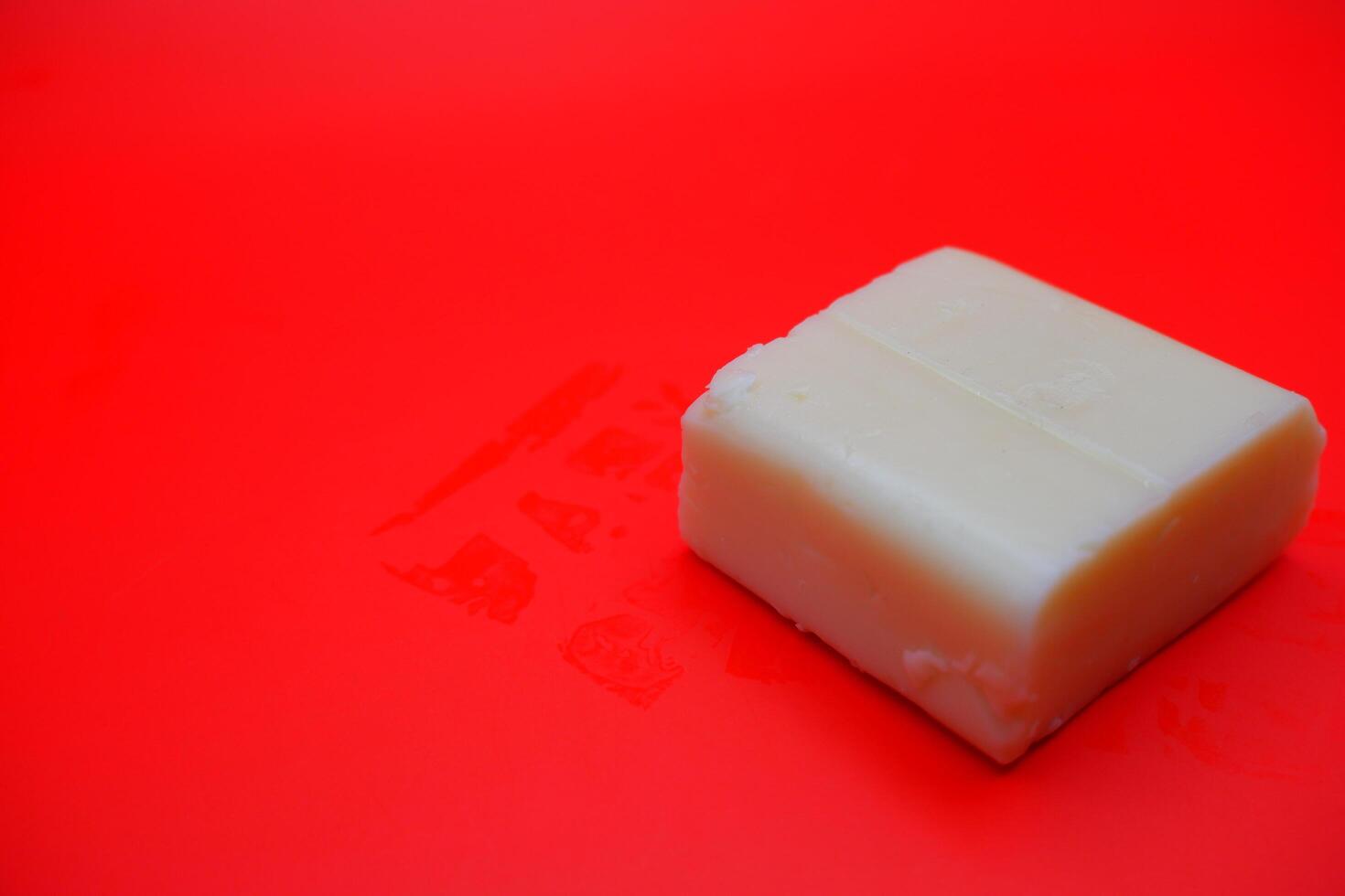 cube shaped cheese isolated on red background. mozzarella cheese that melts easily photo