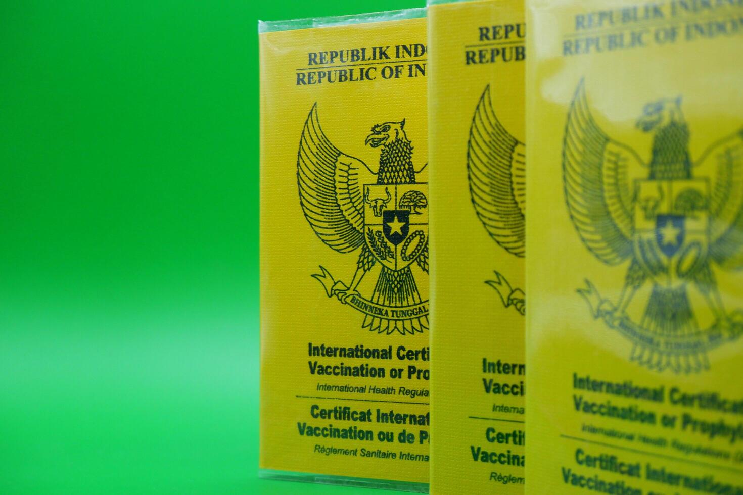 international certificate of vaccination or prophylaxis isolated on green background. 3 yellow books as a sign of vaccination. yellow book of vaccines from indonesia photo
