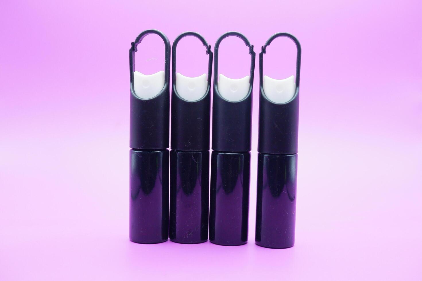 mini sprayer bottles isolated on purple background. four sprayer bottles with hangers photo