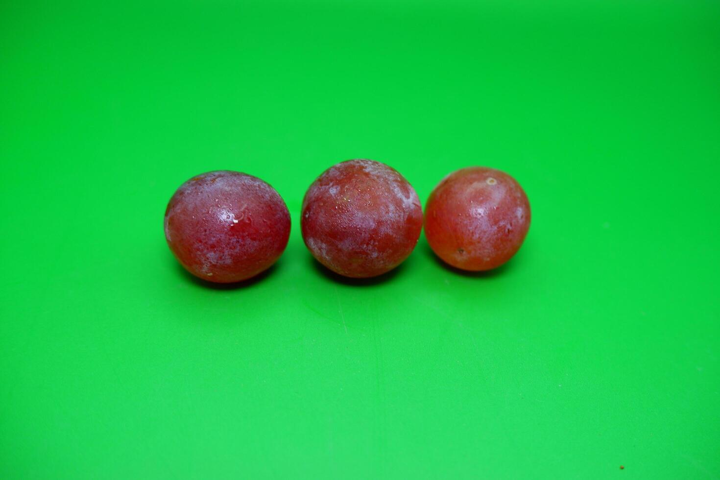 3 grapes isolated on green background. Fresh purple grapes. photo