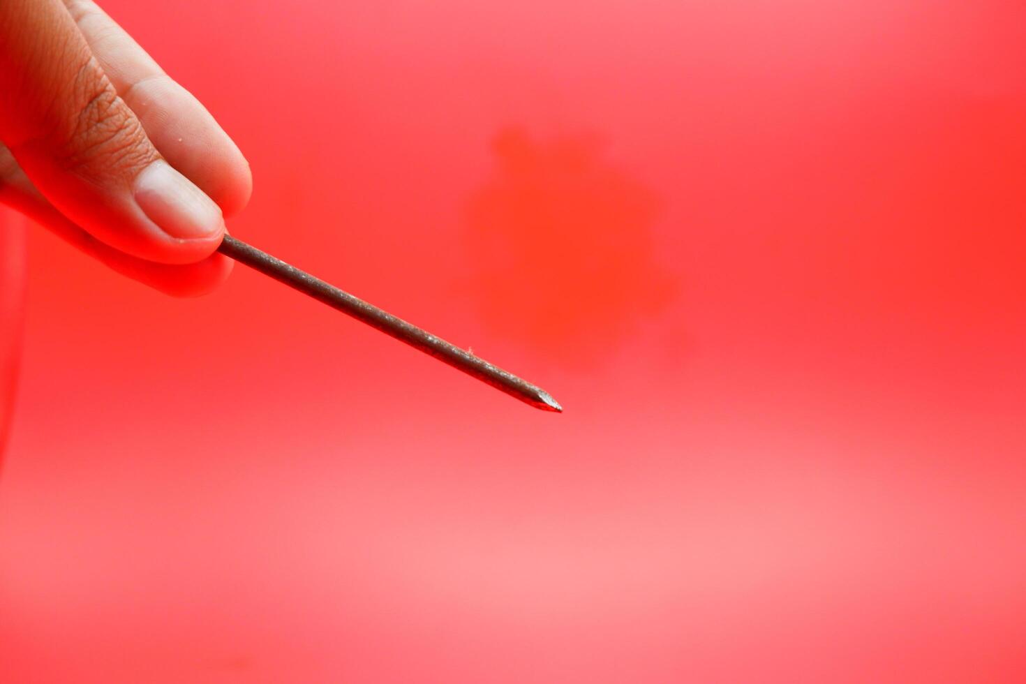 rusty nail isolated on red background. rusty nail with a length of approximately 10 cm photo