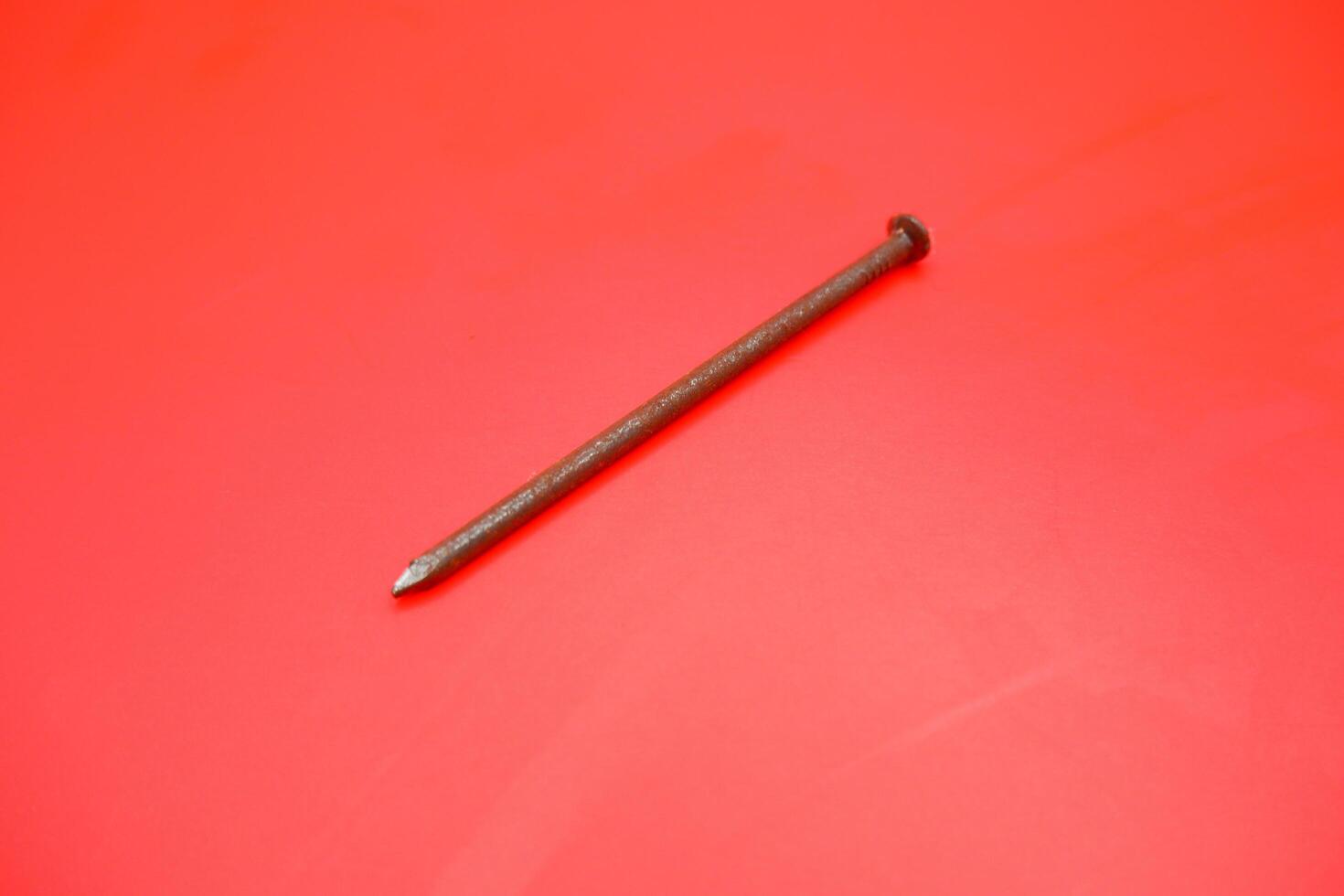 rusty nail isolated on red background. rusty nail with a length of approximately 10 cm photo