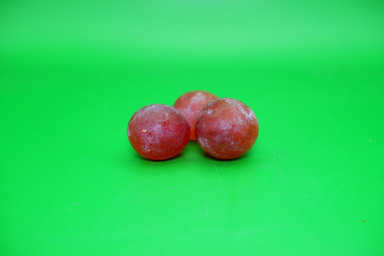 3 grapes isolated on green background. Fresh purple grapes. photo